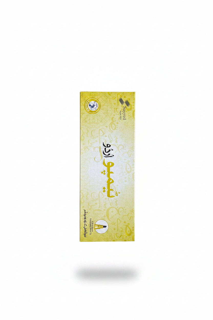 A hand holding a yellow rectangular box of Syed Al-Falah Makhraj incense sticks, with a store shelf filled with blue and white cartons in the blurred background.